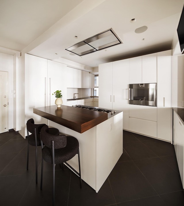 71 Park Ave Unit 10-A, New York City, NY 10016 - kitchen featuring butcher block countertops, oven, a kitchen breakfast bar, and dark tile patterned floors