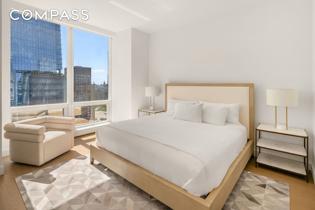 bedroom with a view of city and wood finished floors