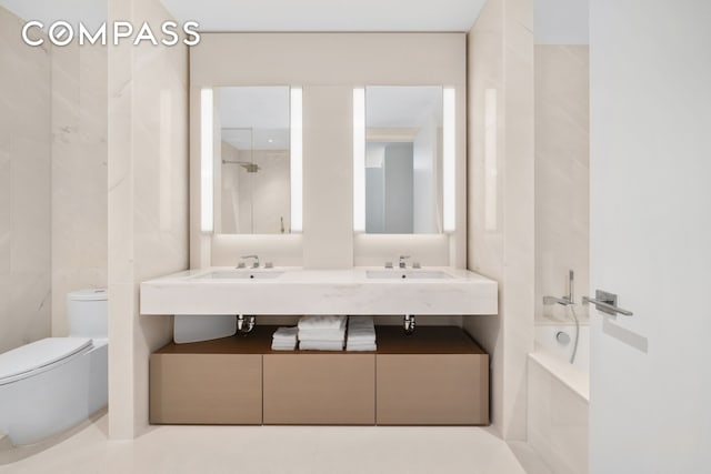 bathroom with double vanity, a sink, a tub, and toilet