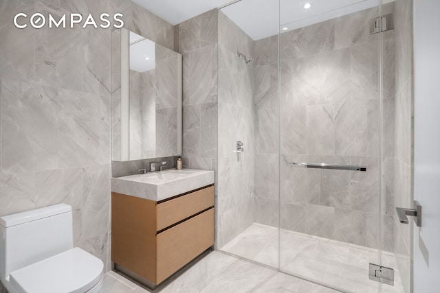 bathroom featuring vanity, a stall shower, toilet, and tile walls