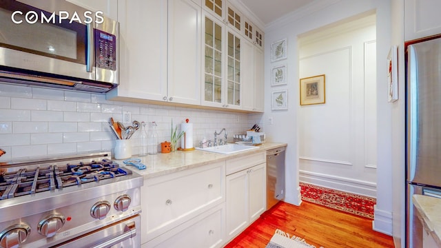 kitchen featuring a sink, crown molding, stainless steel appliances, and white cabinets