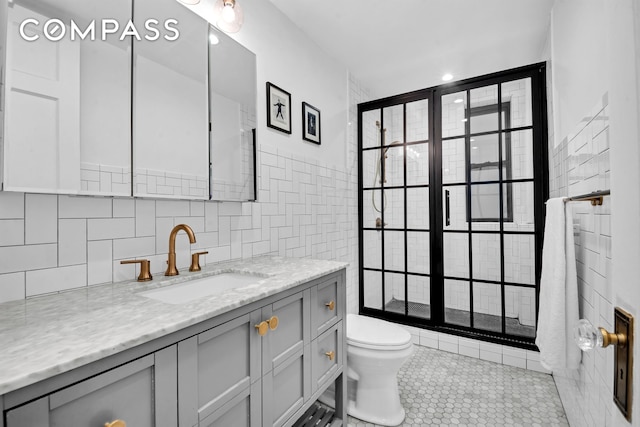 bathroom with tile patterned flooring, vanity, toilet, and tile walls