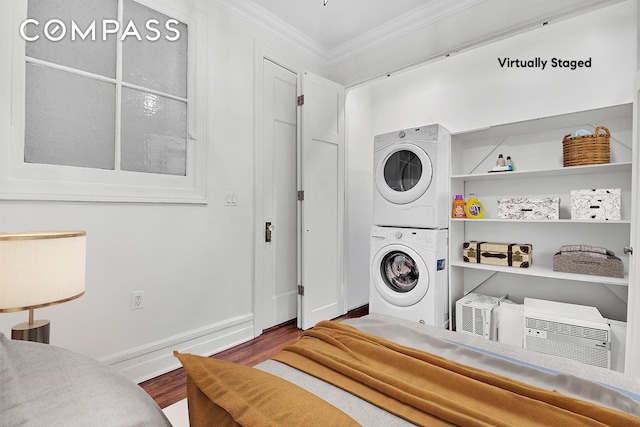 laundry room featuring laundry area, ornamental molding, stacked washer / drying machine, and wood finished floors