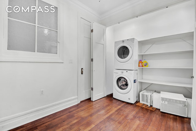 washroom with stacked washing maching and dryer, crown molding, laundry area, and wood finished floors