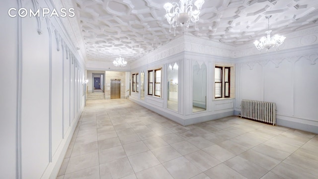 corridor featuring light tile patterned flooring, a notable chandelier, radiator, and a decorative wall