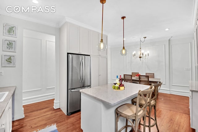 47 Fort Washington Ave Unit 55, New York City, NY 10032 - kitchen featuring stainless steel fridge, a decorative wall, light wood-style floors, crown molding, and white cabinetry