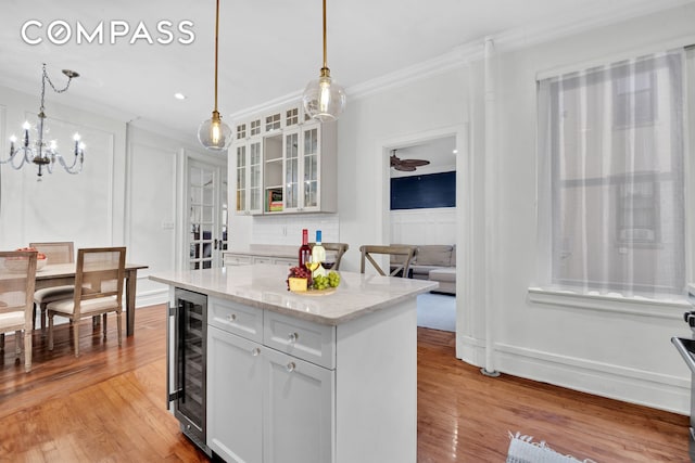 kitchen with crown molding, white cabinetry, beverage cooler, and light wood-type flooring
