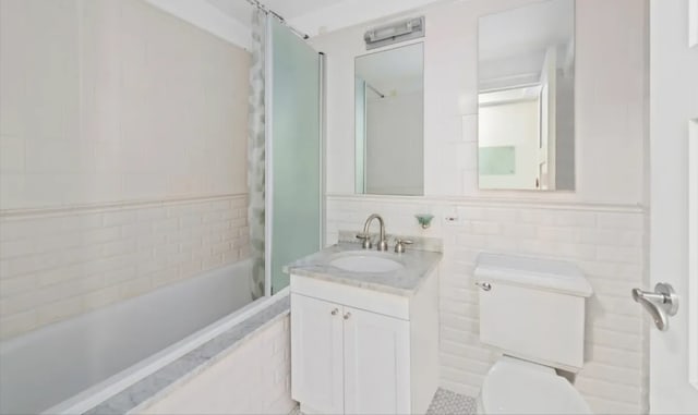 full bath featuring tile walls, toilet, tub / shower combination, and vanity