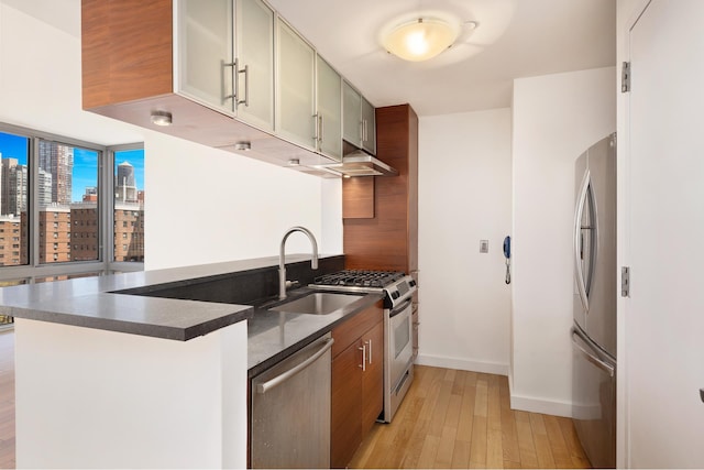 225 W 60th St Unit 14E, New York City, NY 10023 - kitchen with appliances with stainless steel finishes, dark countertops, light wood-style floors, extractor fan, and a peninsula