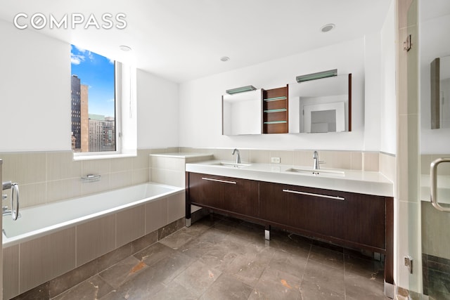 bathroom with double vanity, a sink, a garden tub, and a shower stall