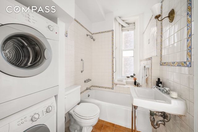 bathroom featuring shower / tub combination, tile patterned floors, stacked washer / dryer, and toilet