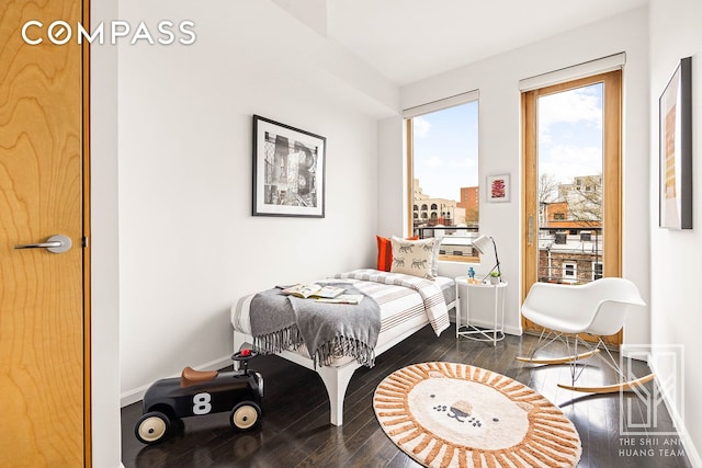 bedroom with dark wood-style flooring, baseboards, and access to exterior