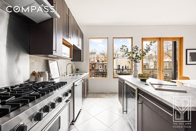 kitchen featuring dark brown cabinetry, a sink, stainless steel appliances, tasteful backsplash, and wine cooler