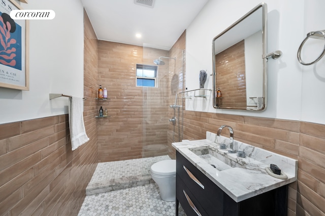 324 E 50th St Unit 6D, New York City, NY 10022 - bathroom with tile walls, toilet, vanity, tiled shower, and tile patterned floors
