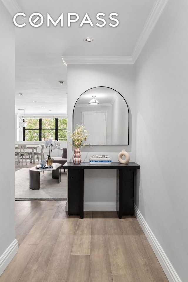 interior space with crown molding, baseboards, and wood finished floors