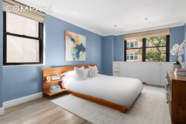 bedroom featuring crown molding, baseboards, and light wood finished floors
