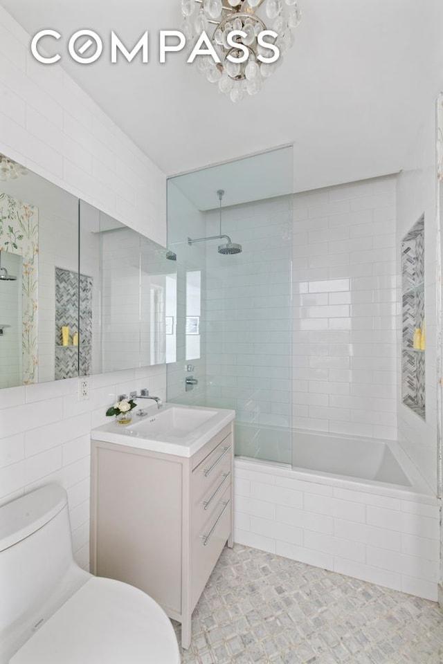 full bath featuring a chandelier, tiled shower / bath, toilet, vanity, and tile patterned floors