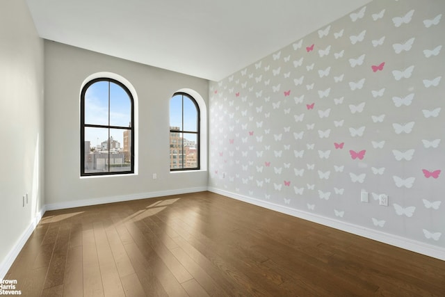 unfurnished room featuring dark wood-type flooring, baseboards, and wallpapered walls