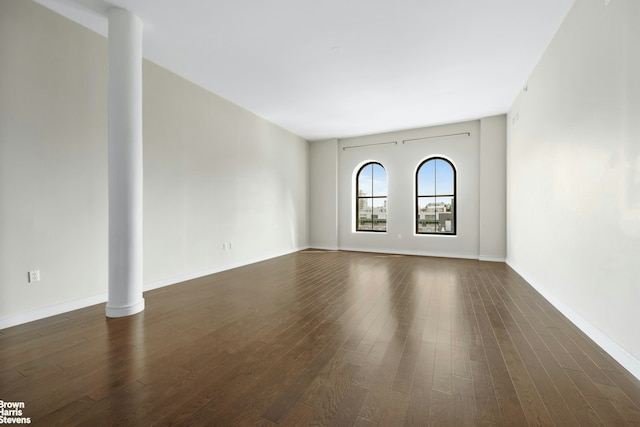 spare room featuring baseboards and dark wood-style floors