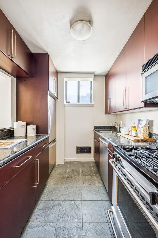 kitchen featuring visible vents, baseboards, a sink, dark stone countertops, and stainless steel appliances