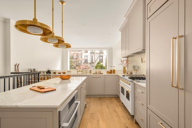 38 Garfield Place, New York City, NY 11215 - kitchen with premium appliances, a center island, light wood-style floors, light stone counters, and hanging light fixtures