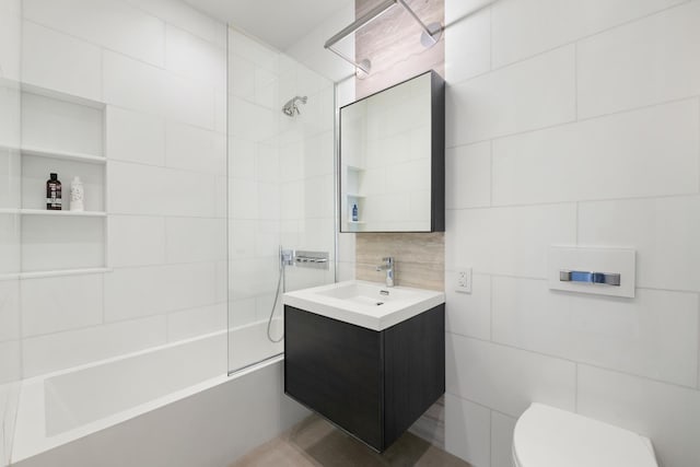 bathroom with shower / bathtub combination, toilet, tile walls, and vanity