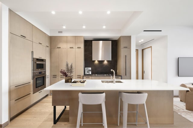 kitchen featuring a breakfast bar area, a sink, modern cabinets, and light wood finished floors