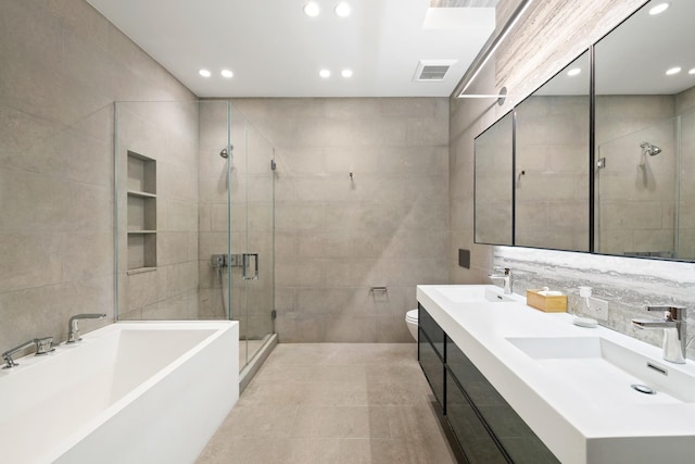 bathroom with visible vents, a sink, a shower stall, and tile walls