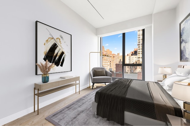 bedroom with baseboards, a view of city, and wood finished floors