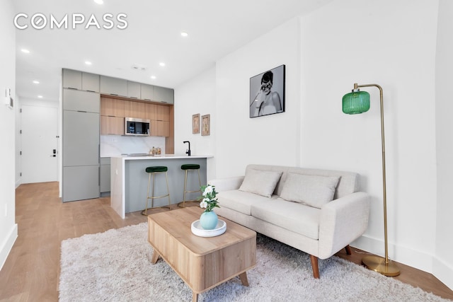 living room with baseboards, recessed lighting, and light wood-style flooring