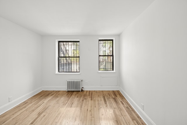 spare room featuring baseboards, light wood finished floors, and radiator heating unit