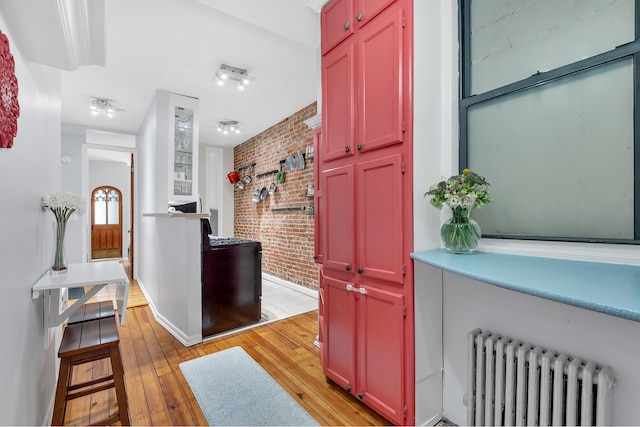 206 E 90th St Unit 4W, New York City, NY 10128 - hallway with radiator heating unit, brick wall, and light wood-style flooring