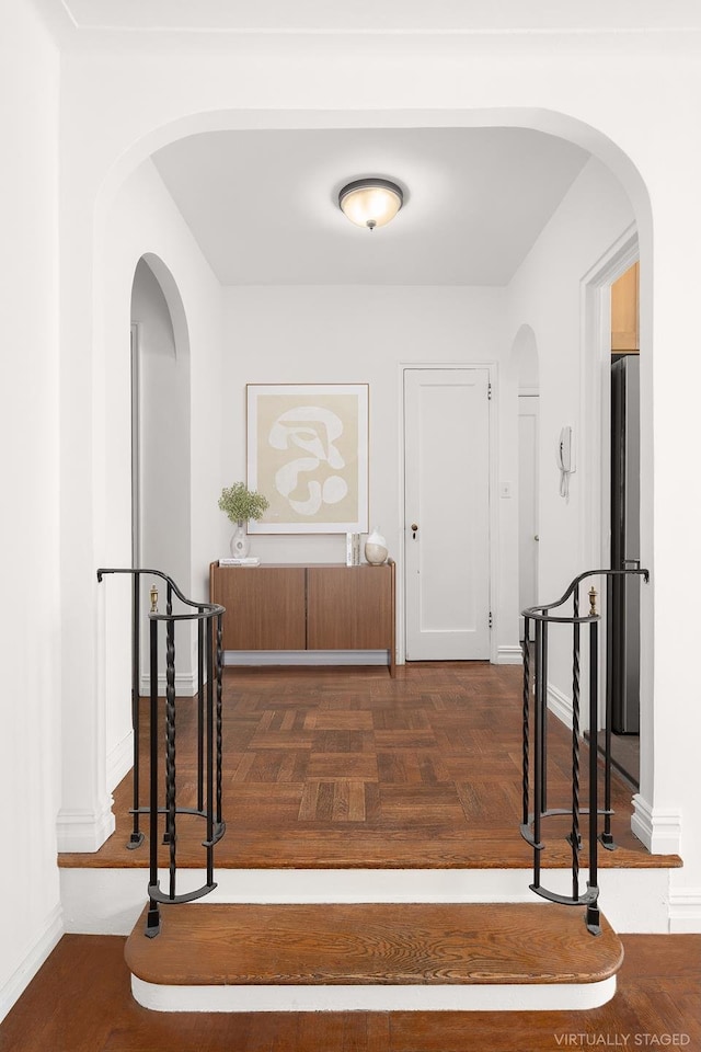 hallway with arched walkways and baseboards
