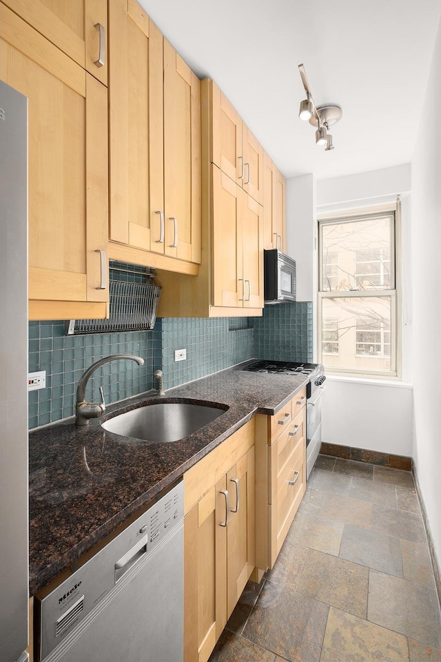 kitchen featuring tasteful backsplash, a sink, stone tile flooring, light brown cabinets, and stainless steel appliances