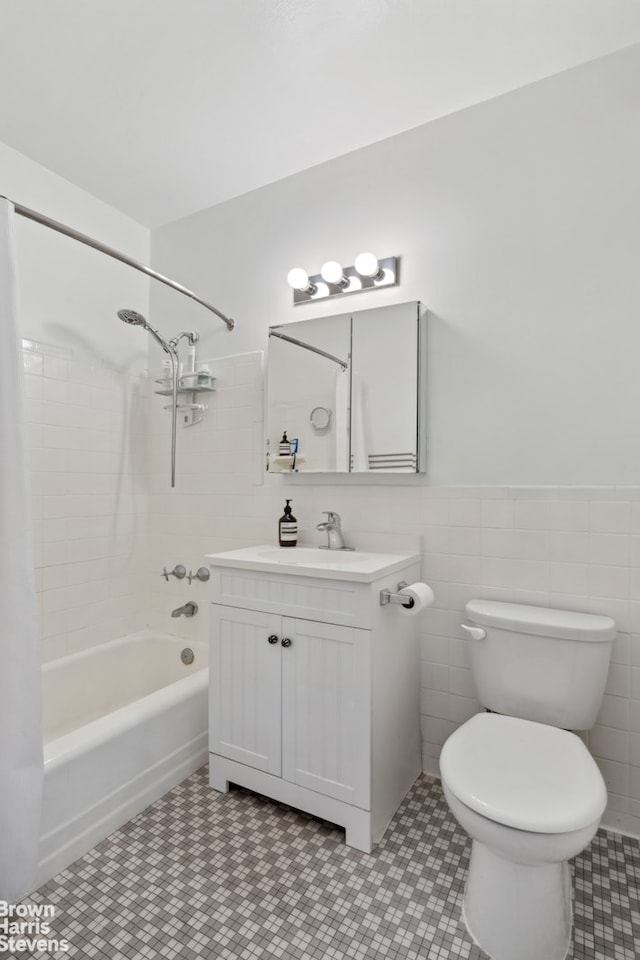 full bathroom with vanity, wainscoting, shower / bathtub combination, toilet, and tile walls