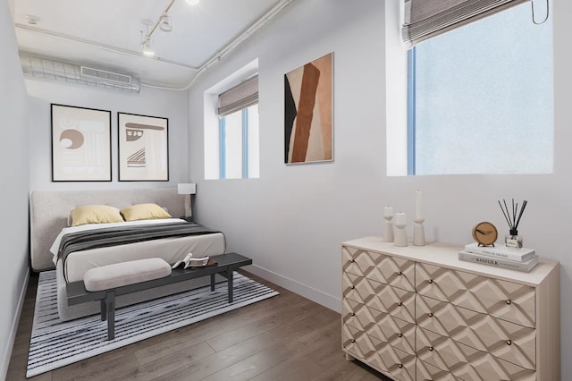 bedroom featuring baseboards, rail lighting, visible vents, and wood finished floors
