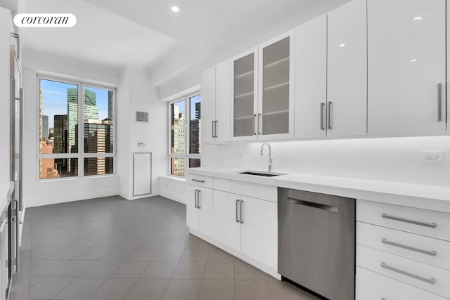 kitchen featuring stainless steel dishwasher, light countertops, tile patterned floors, baseboards, and a sink