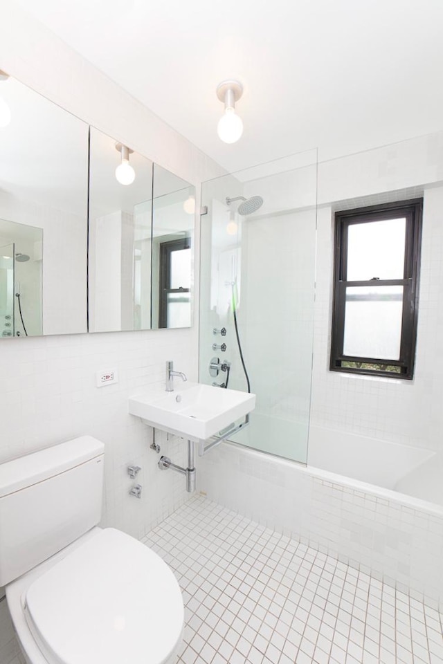 full bathroom with a sink, bathtub / shower combination, toilet, tile patterned floors, and tile walls