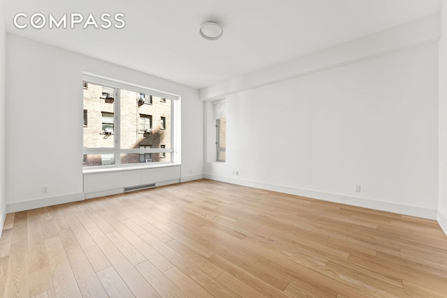 spare room featuring light wood-style floors, baseboards, and visible vents