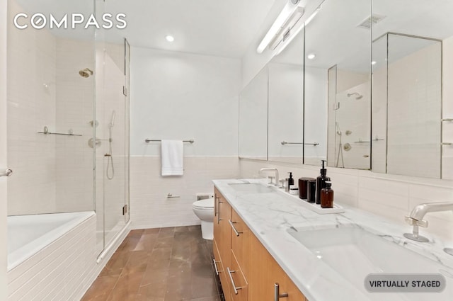 full bath with a sink, a stall shower, toilet, and tile walls