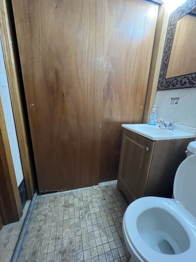 half bath featuring toilet, vanity, and tile patterned flooring