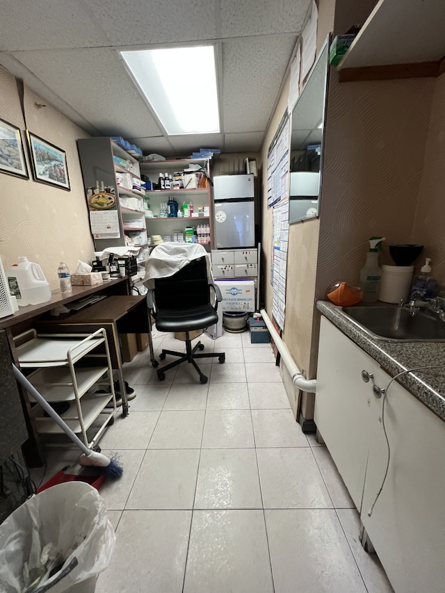 home office featuring a drop ceiling, a sink, and light tile patterned flooring