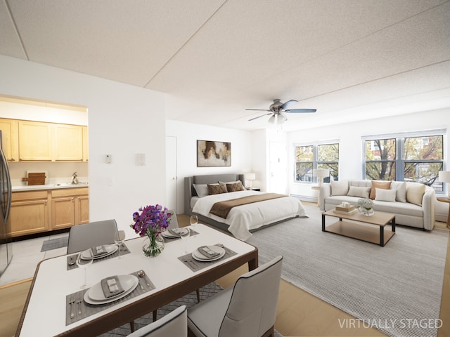 bedroom featuring ceiling fan, stainless steel fridge, connected bathroom, a sink, and light wood finished floors