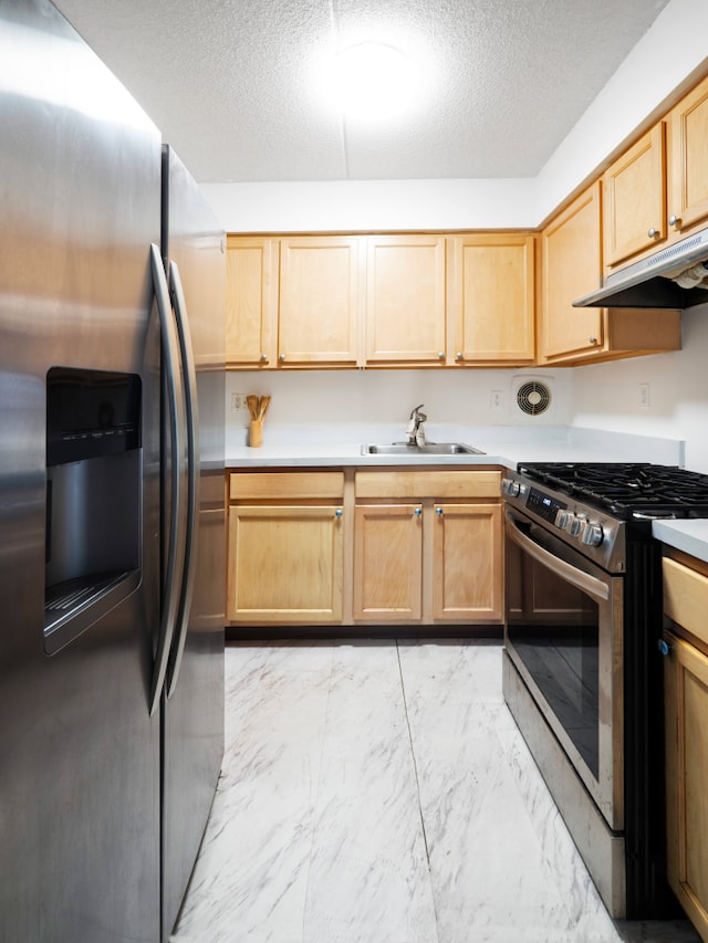 kitchen with a textured ceiling, appliances with stainless steel finishes, a sink, marble finish floor, and under cabinet range hood