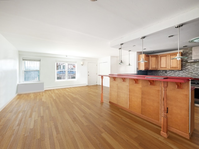 kitchen featuring dark countertops, tasteful backsplash, a kitchen bar, and light wood-style flooring