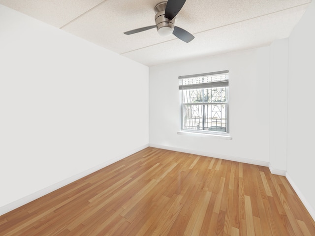 spare room featuring a textured ceiling, baseboards, ceiling fan, and light wood-type flooring
