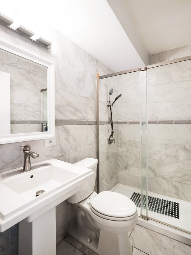 full bathroom with a sink, tile walls, toilet, and a shower stall