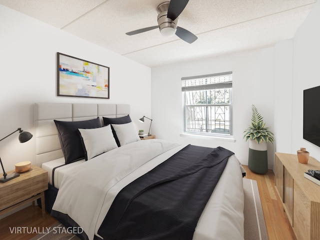 bedroom featuring light wood-style floors, a textured ceiling, and ceiling fan
