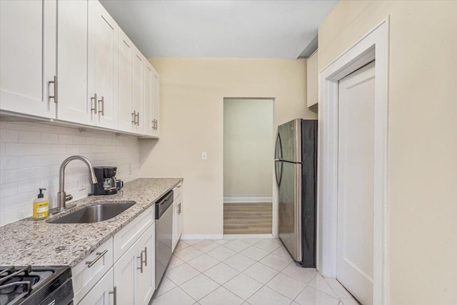 kitchen featuring light stone countertops, white cabinets, tasteful backsplash, a sink, and appliances with stainless steel finishes