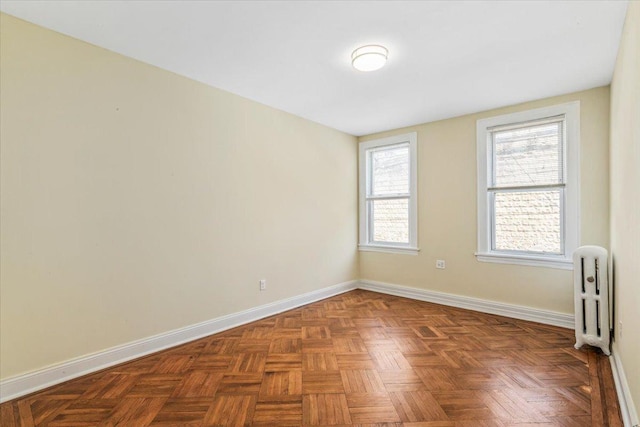 unfurnished room featuring radiator heating unit and baseboards
